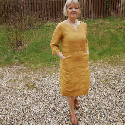 Anbi Jette i varm gul hørkjole og brune loafers
