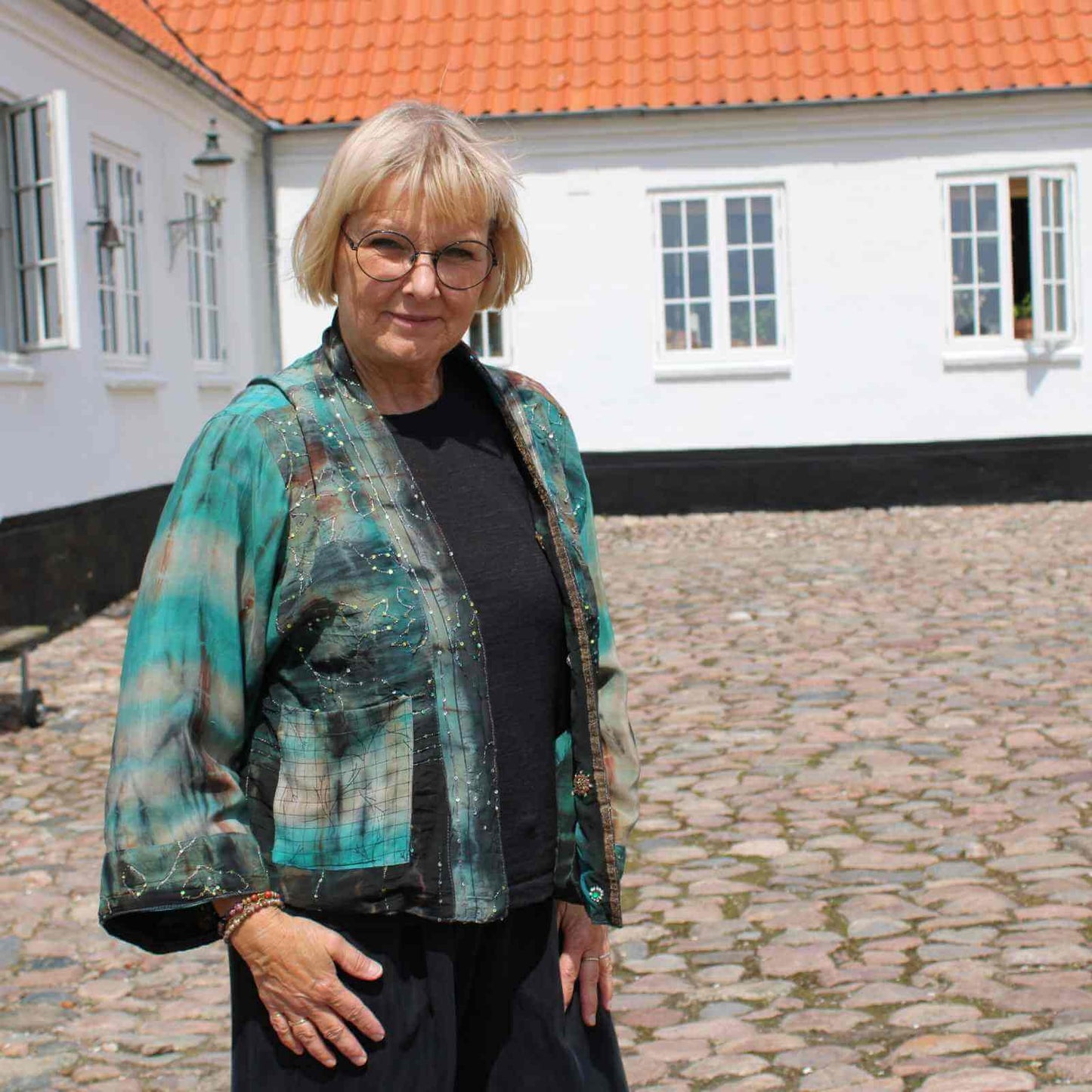 grøn silkejakke over sort tøj på Anbi Jette på gårdsladsen