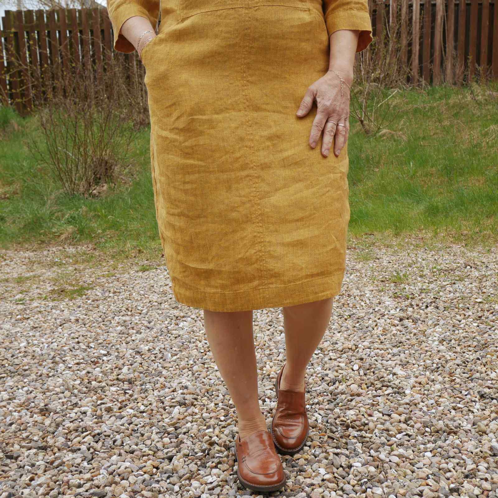 nederdel på varm gul hørkjole , brune loafers på grus baggrund