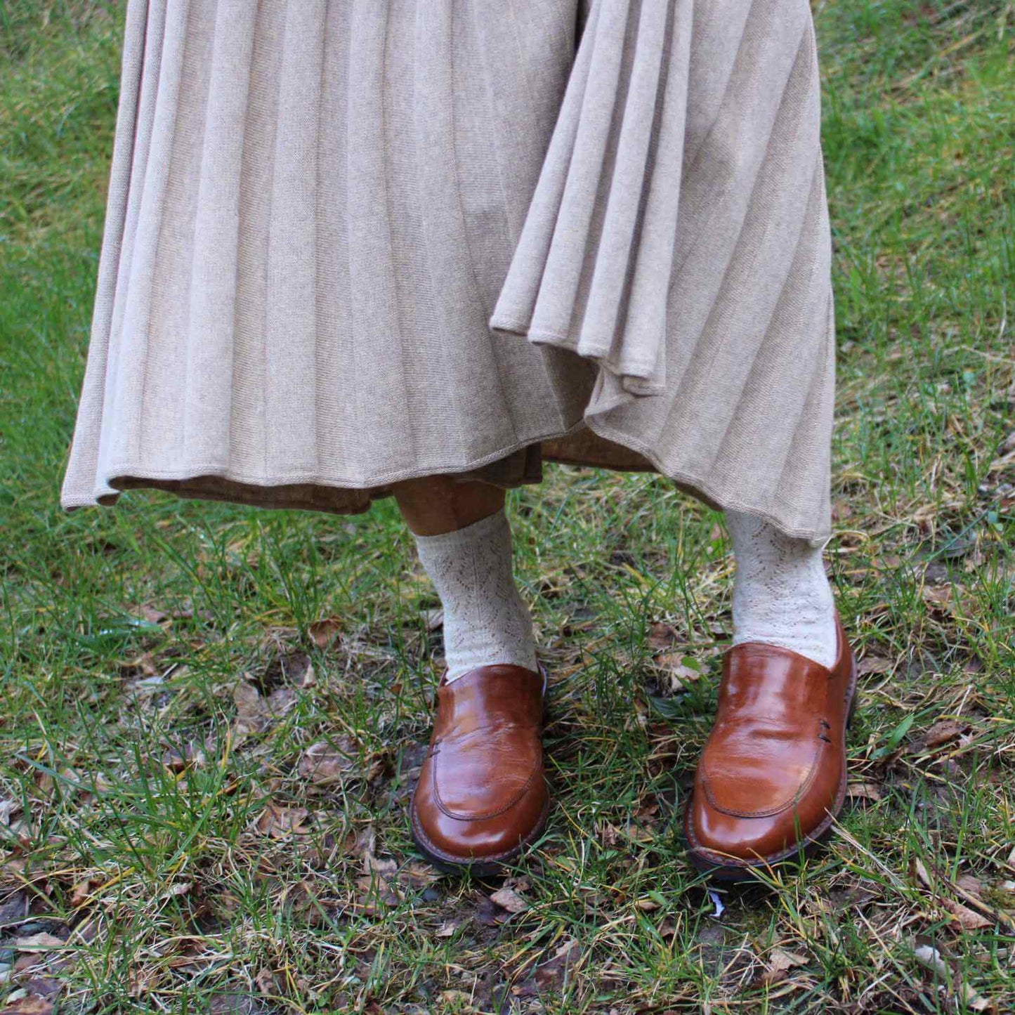Brune skind loafers med små soller og lys nederdel på græs baggrund