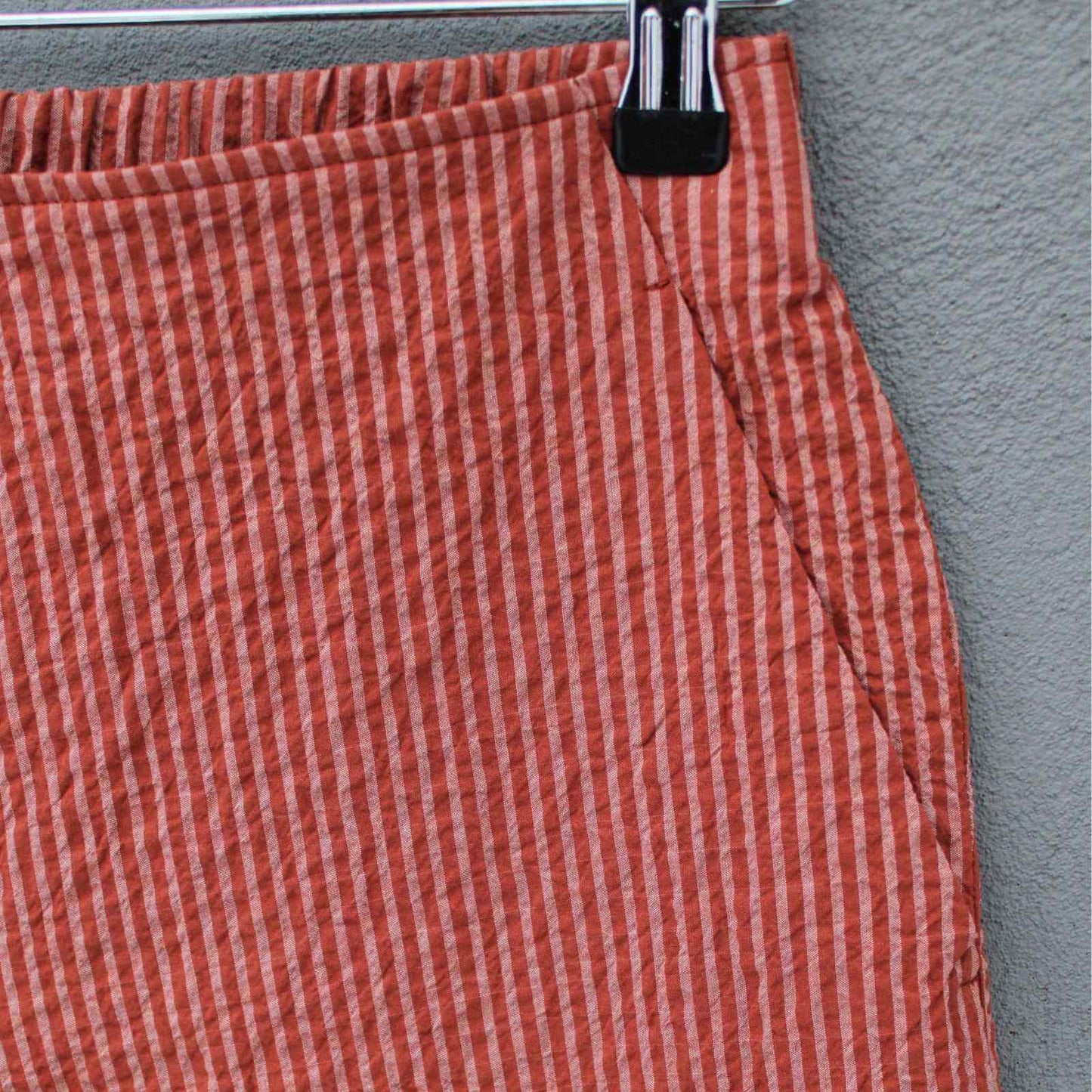 Skrå sidelomme detalje på kopperfarvet bukser fra Oska