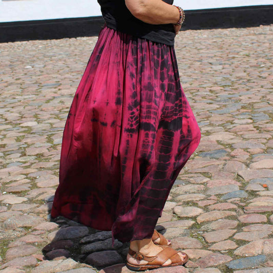 pink og sort tie dye silkenederdel på kvinde med brune sandaler.