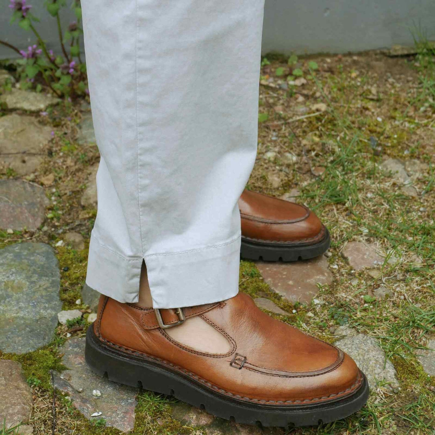 slids i ben på lyse bukser med brune sko til på græs