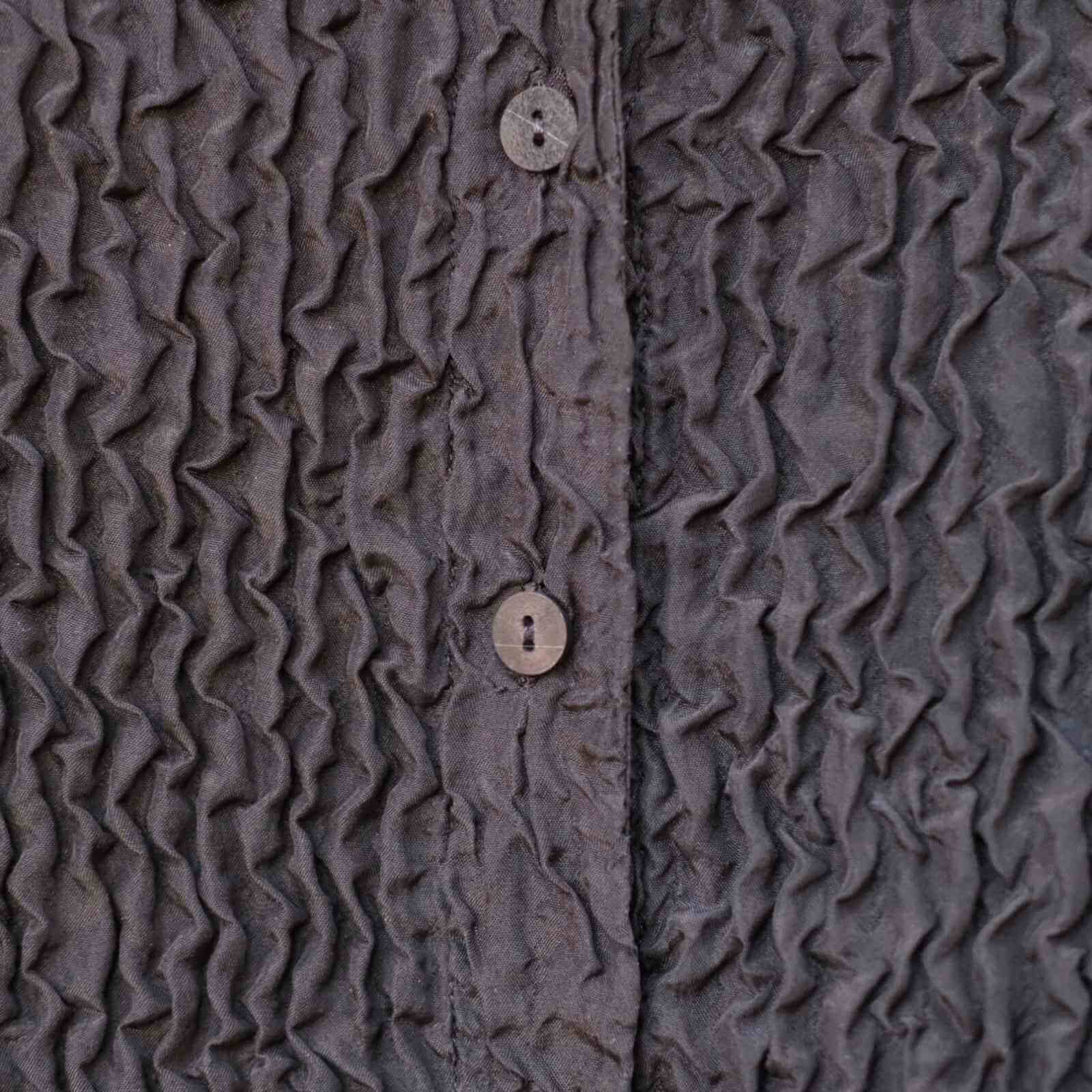crep stof detalje af sort løs silke bluse med knappper